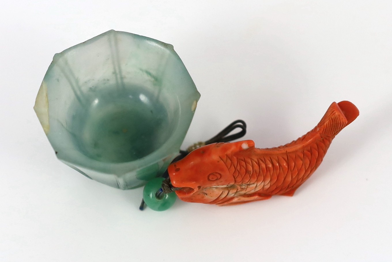 A Chinese jadeite small cup and a coral 'fish' pendant, 19th/20th century